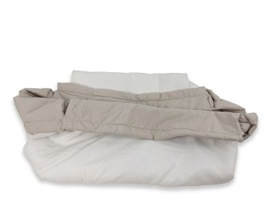 un tas d'oreillers et une couverture posés sur une surface blanche