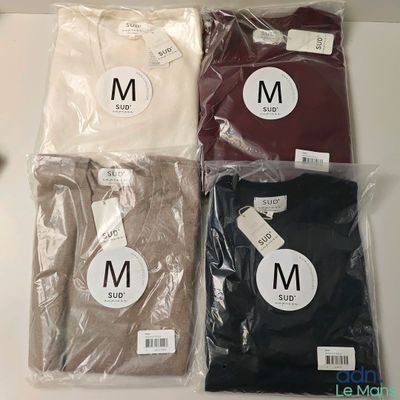trois paires de t-shirts pour homme dans des sacs en plastique posés sur une table