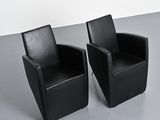 pair of black leather chairs in a room with a white wall