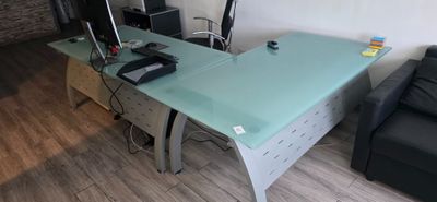 un bureau en verre sur lequel est posé un ordinateur, dans un salon