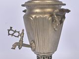 a silver metal urn with a handle on a stand