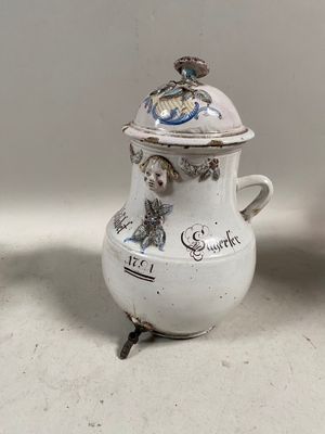 un vase blanc muni d'un couvercle, posé à côté d'un vase surmonté d'une tasse