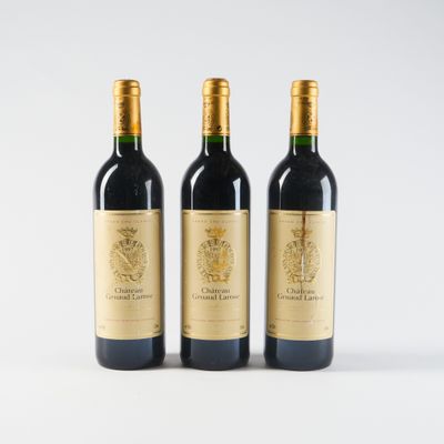 trois bouteilles de vin rouge sont posées côte à côte sur une surface blanche