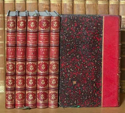 plusieurs vieux livres posés sur une étagère devant une rangée de vieux livres