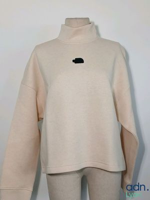 un pull blanc avec un patch noir sur la poitrine
