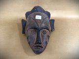 a wooden mask hanging on the wall of a room