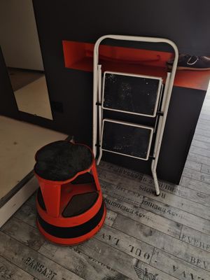 un tabouret rouge et une chaise noire et blanche dans une pièce