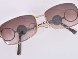 lunettes de soleil posées sur une surface blanche, avec une branche noire et un verre marron