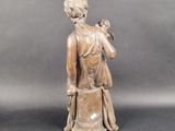 bronze statue of a woman holding a bird on her shoulder