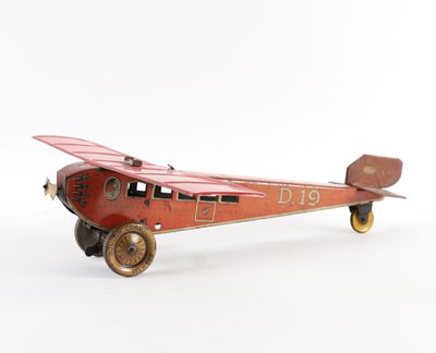 petit avion jouet muni de roues, posé sur une surface blanche, avec un fond blanc