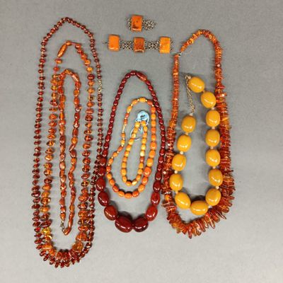 trois colliers composés de perles orange et jaunes, posés sur un fond blanc