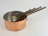 three metal pots with spoons in them on a white surface