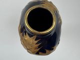 a black and gold vase sitting on a white surface