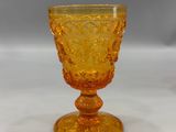 an orange glass goblet sitting on top of a white table