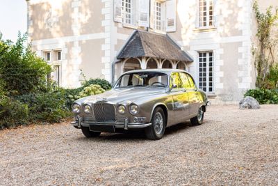 une voiture argentée garée devant une grande maison