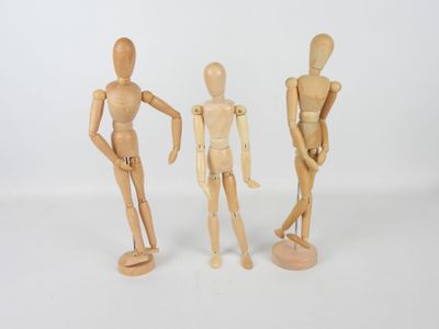 trois mannequins en bois placés les uns à côté des autres
