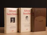 deux livres posés sur une table, sur fond noir, et un livre marron