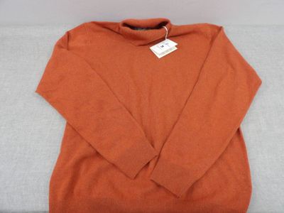 an orange sweater sitting on top of a white couch