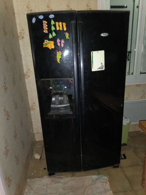 a black refrigerator in the corner of a room with a mirror