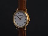 a close up of a gold wrist watch with roman numerals