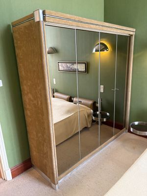 a large mirrored closet in the corner of a bedroom