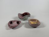 three different colored bowls sitting next to each other on a white surface