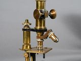 an antique brass microscope with a wooden base and a metal stand