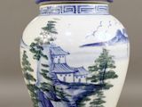 a blue and white vase with a landscape on it
