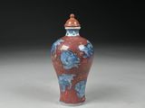 a red and blue vase sitting on top of a white table