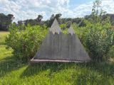 a concrete triangle in the middle of a grassy field
