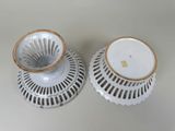 two white vases with gold rims on a table