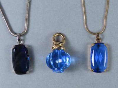 trois colliers composés de perles de verre bleues et d'une chaîne en or