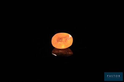 a close up of an orange stone on a black surface