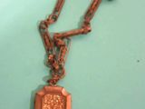 un collier ancien avec un médaillon suspendu à une chaîne, posé sur une table