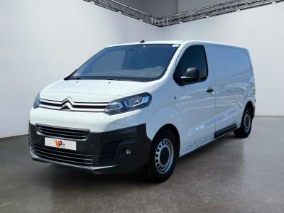 La camionnette blanche est garée dans une grande pièce aux murs blancs.