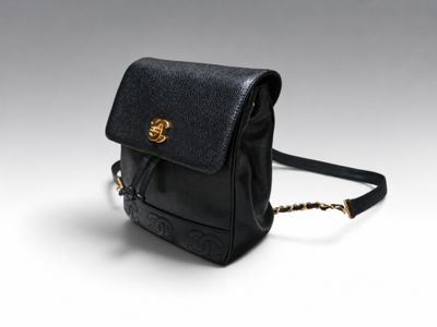 un petit sac à main noir muni d'une chaîne dorée, sur fond blanc