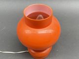 an orange vase on a table with a white cord attached to it