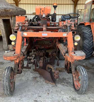 un tracteur équipé d'une charrue, dans une grange