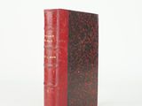 un vieux livre à la couverture rouge posé sur une surface blanche