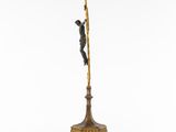 a bronze statue of a man on a pole with a spear