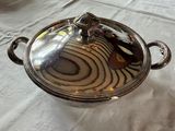 un plat en argent muni d'un couvercle, posé sur une table
