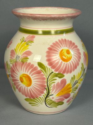 un vase blanc orné de fleurs roses et jaunes peintes dessus