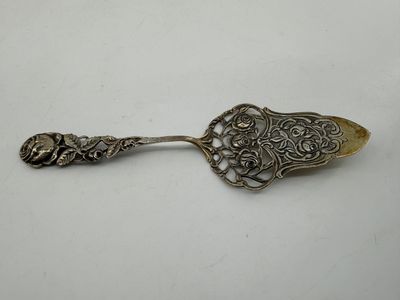 a silver spoon with ornate design on it sitting on a white surface
