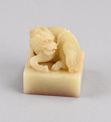 une petite figurine sculptée représentant un chat, posée sur une boîte