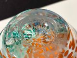 a close up of a glass vase with orange and green designs