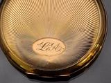 a gold plated pocket watch with a monogram on it