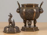 a bronze statue of a dog and a vase on a table