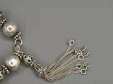 un gros plan sur un collier en argent orné de perles