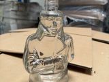 a glass bottle with a statue on it sitting on a table