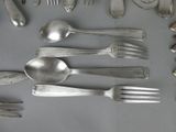 a lot of silver spoons and forks laid out on a table